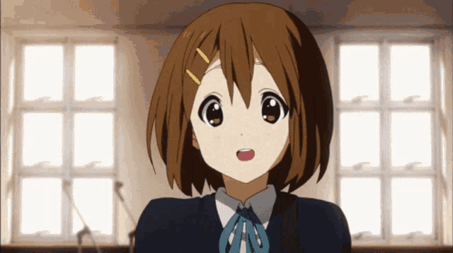 a brown haired anime girl with a blue bow on her neck stands in front of a window