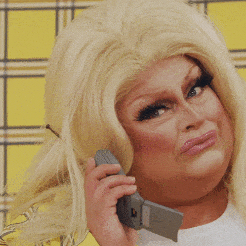a drag queen talking on a cell phone while wearing a yellow plaid jacket
