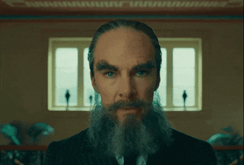 a man with a beard and moustache looks at the camera