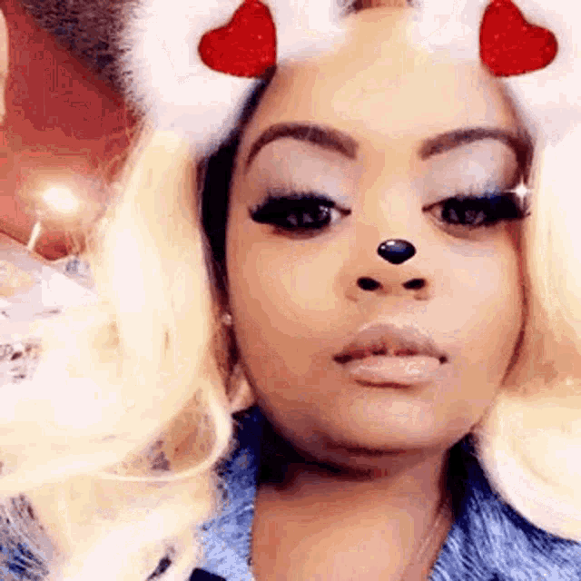 a close up of a woman wearing a snapchat filter with hearts on her face .