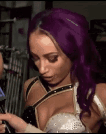 a woman with purple hair is holding a microphone and looking at her phone .