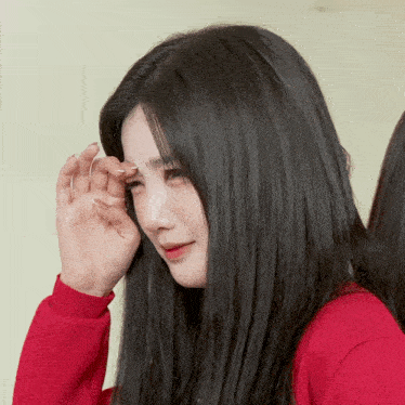 a woman in a red sweater is covering her face with her hand