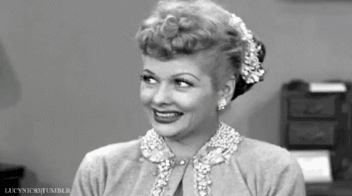 a black and white photo of a woman wearing a pearl necklace and smiling .