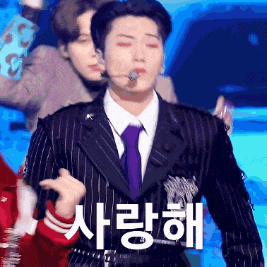 a man in a suit and tie is standing in front of a sign that says ' i love you '