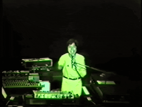 a person in a green shirt is singing into a microphone on a stage