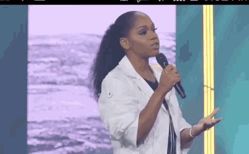 a woman is speaking into a microphone on a stage