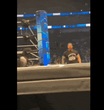 a man in a wrestling ring wearing a t-shirt that says ' roman reigns '