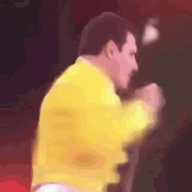 a man in a yellow jacket is standing in front of a microphone on a stage .