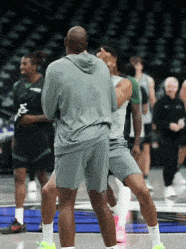 a man in a grey shirt is standing on a basketball court with other players