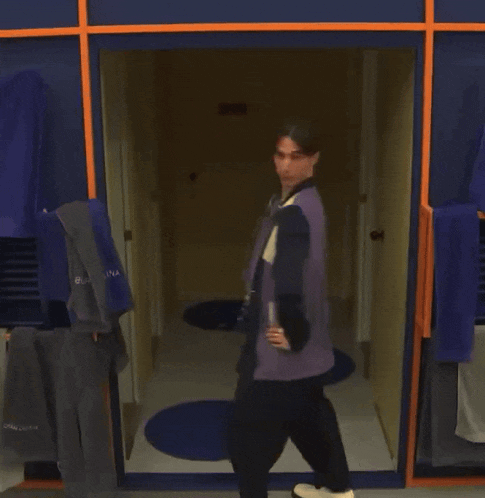 a man standing in a locker room with a jacket that says ' balenciaga ' on it