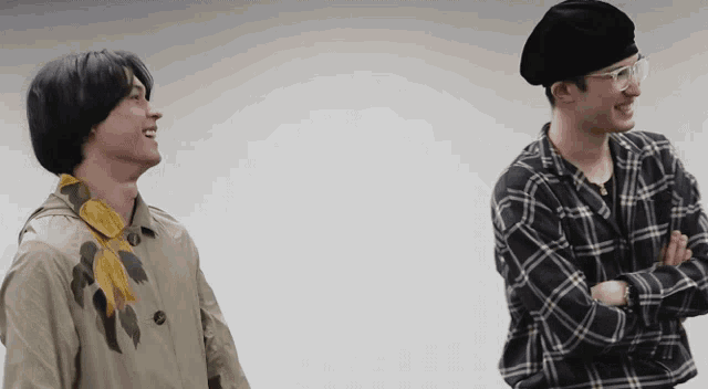 two men standing next to each other one wearing a plaid shirt