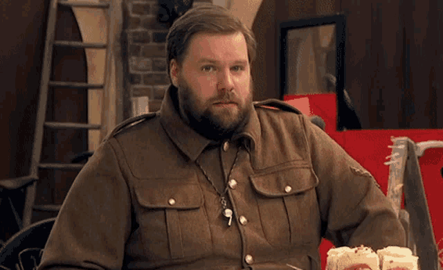 a man in a military uniform is sitting at a table eating cupcakes