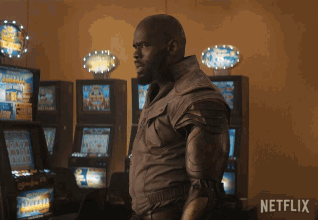 a man standing in front of a row of slot machines with netflix written on the bottom