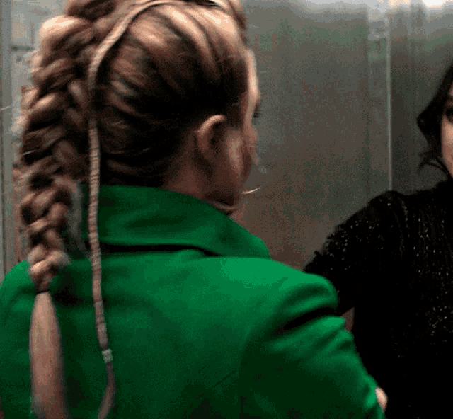 a woman in a green jacket with a braided ponytail