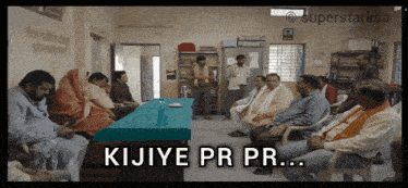 a group of people sitting around a table with the words kijiye pr pr