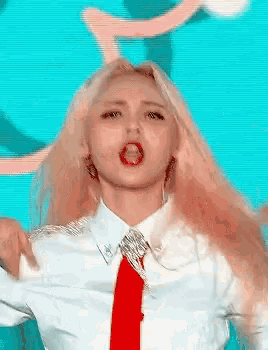 a woman with long blonde hair is wearing a white shirt and a red tie .