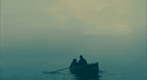 two men are in a small boat in the middle of the ocean