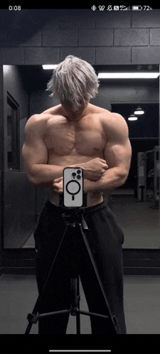 a shirtless man is taking a picture of himself in front of a mirror ..