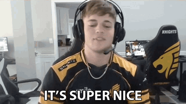 a man wearing headphones and a shirt that says it 's super nice is sitting in a chair .