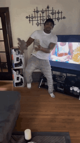 a man is dancing in front of a tv in a living room with boxes of joystick controllers