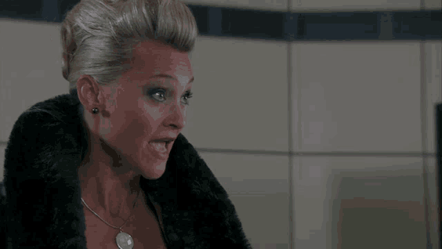 a woman wearing a black fur coat and a necklace with a pendant