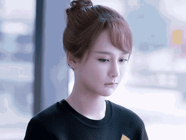 a woman with her hair in a bun is wearing a black shirt