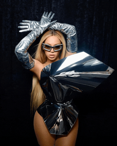 a woman wearing silver gloves and sunglasses holds up a silver object