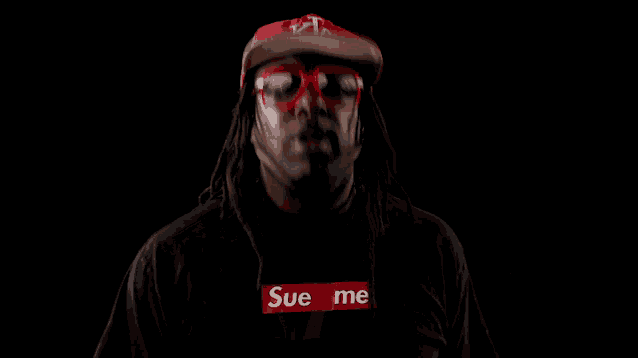 a man wearing sunglasses and a supreme shirt