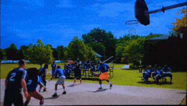 a group of people are playing basketball in a park and one of the players has the number 2 on his back