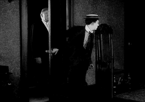 two men in suits and hats are standing in front of a door