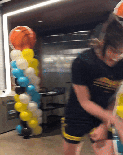 a woman in a black shirt that says ' abercrombie & fitch ' on it stands in front of balloons