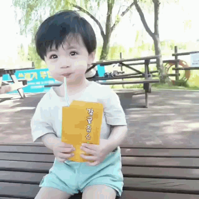 a little boy drinking through a straw from a yellow bottle