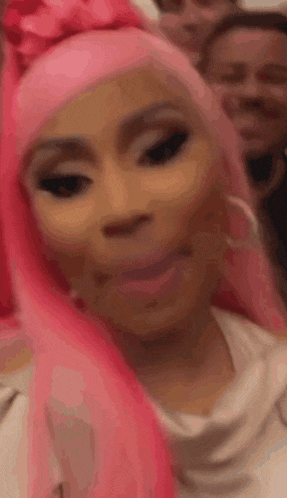 a woman with pink hair is making a funny face while standing in front of a group of people .