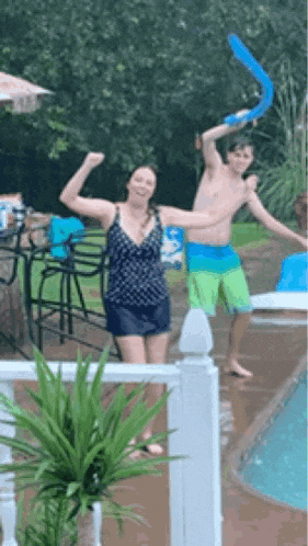 a man and a woman are standing in front of a pool
