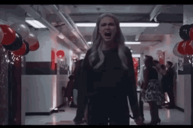 a woman is screaming in a hallway with balloons on the walls .