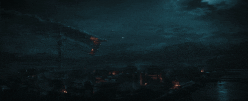 a dark landscape with a few lights on the buildings
