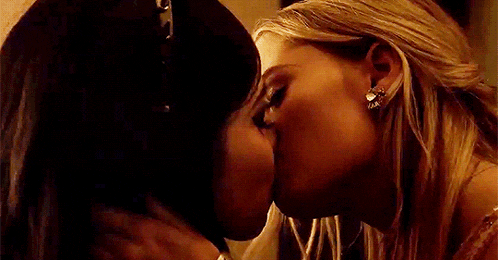 a couple of women are kissing each other on the cheek .