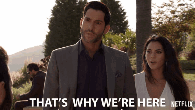 a man in a suit stands next to a woman with the words that 's why we 're here netflix below him