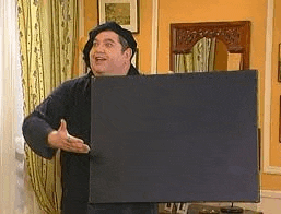 a man is standing in a living room holding a large black box .