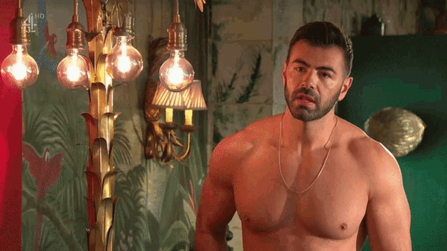 a shirtless man stands in front of a chandelier with a hd logo on the bottom right