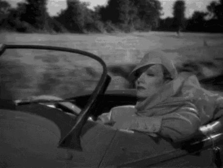 a black and white photo of a woman in a convertible