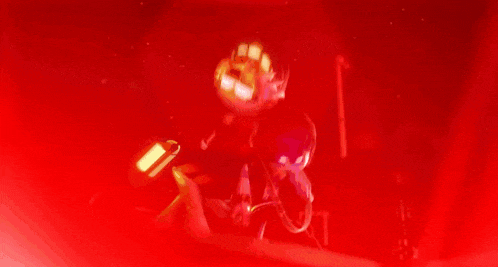 a person is standing in a dark room with a red light coming from the ceiling .