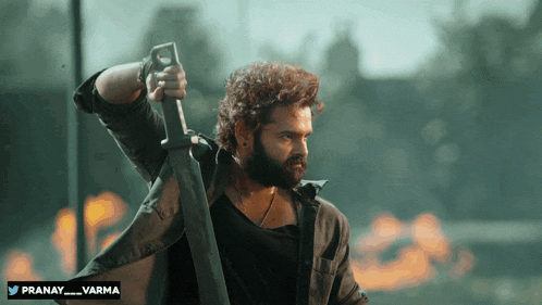a man with a beard is holding a large sword with the name pranay written below him