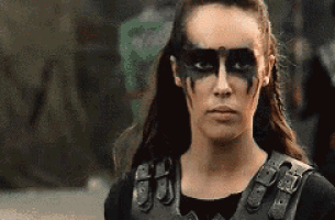 a woman with face paint on her face is wearing a leather vest and a black shirt .