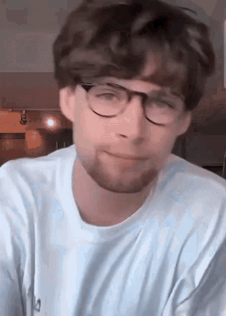 a man wearing glasses and a white shirt with the letter l on it