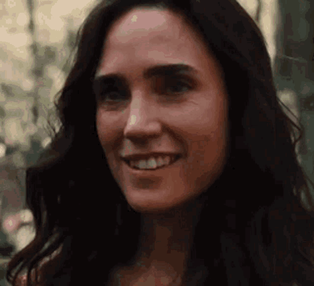 a close up of a woman 's face smiling in a forest .