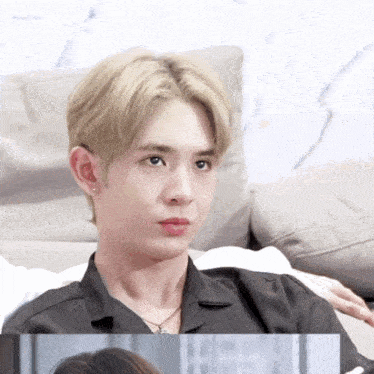 a man with blonde hair is sitting on a couch and looking at the camera