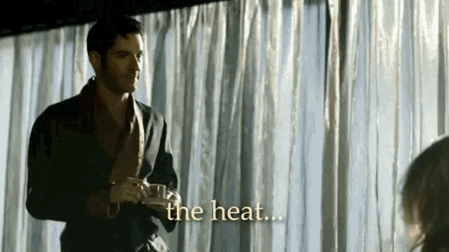 a man in a robe is standing in front of a curtain holding a cup of coffee .