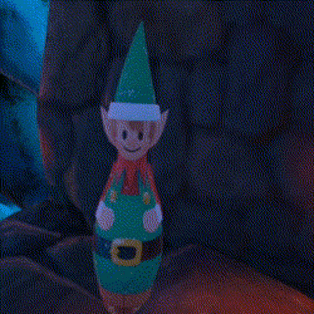 a person is holding a toy elf with a green hat and overalls .