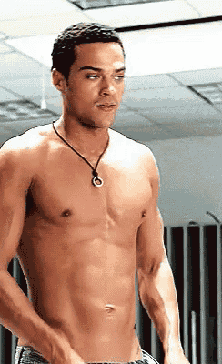 a shirtless man wearing a necklace with a ring on it